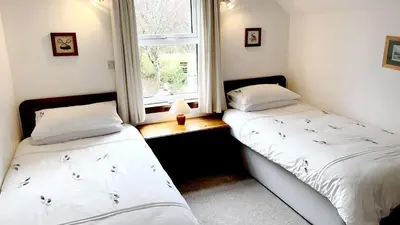 two beds in a room with a window at Craobh Haven Cottages in Craobh Haven
