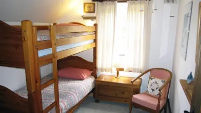 a bedroom with a bunk bed and a chair at Craobh Haven Cottages in Craobh Haven