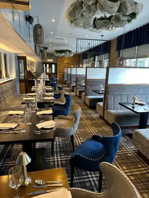 a restaurant with long tables and blue chairs at The Tudor Hotel in Airdrie