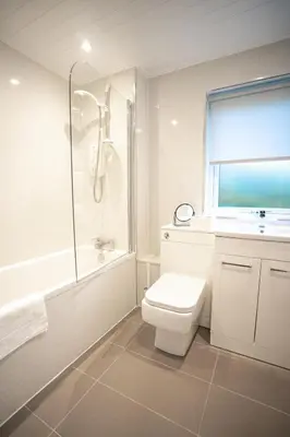 a bathroom with a toilet and a shower and a sink at Bonnie Apartment in Coatbridge