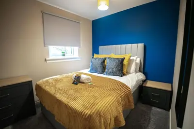 a bedroom with a bed with a blue wall at Bonnie Apartment in Coatbridge