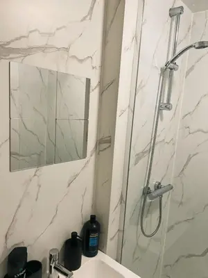 a bathroom with a shower and a sink with a mirror at King Apartment in Falkirk
