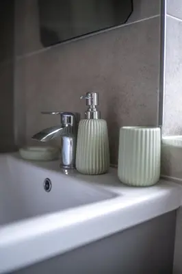 a bathroom sink with two soap dispensers on it at Muirhead House in Motherwell