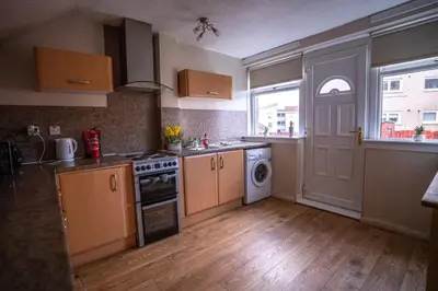 a kitchen with a stove and a washer and dryer at Muirhead House in Motherwell