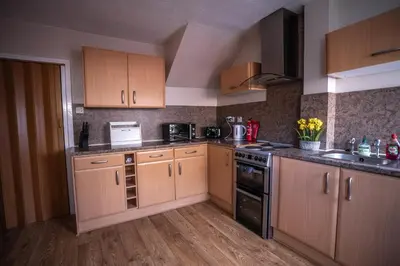 a kitchen with wooden cabinets and a stove top oven at Muirhead House in Motherwell