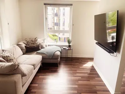 a living room with a couch and a flat screen tv at Modern Two Bed Glasgow Apartment with Free Parking in Glasgow
