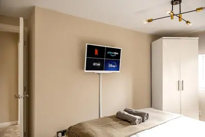 a bedroom with a bed and a tv on the wall at Spacious 3 Bed Home in Glasgow City With Free Parking in Glasgow