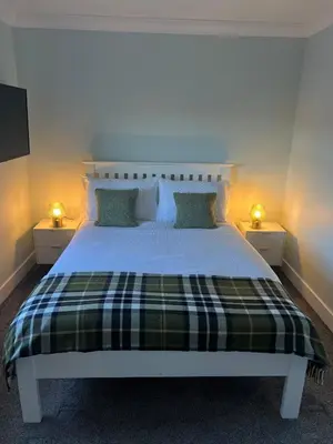 a bedroom with a bed with a plaid blanket at Gellyburn Cottage in Kinross