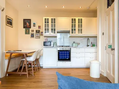 a kitchen with white cabinets and a table at Bright Top Floor 2BR Apartment in Morningside, Easy City Centre Links, Close to University and Royal Hospital in Edinburgh