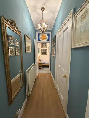 a hallway with blue walls and a mirror on the wall at Bright Top Floor 2BR Apartment in Morningside, Easy City Centre Links, Close to University and Royal Hospital in Edinburgh