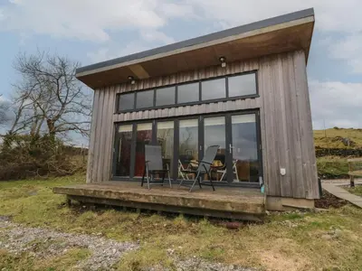 a tiny house with a porch and two chairs at Tirlaggan Studio in Oban