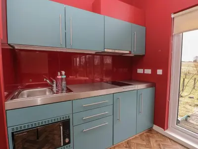 a kitchen with blue cabinets and a sink and a window at Tirlaggan Studio in Oban