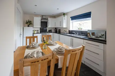 a kitchen with a table and chairs and a kitchen with white cabinets at 3-Bed Home Near Town Center in Stirling