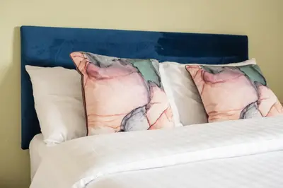 a bed with white sheets and pillows with a blue headboard at 3-Bed Home Near Town Center in Stirling