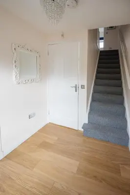 a hallway with a staircase with a white door and wooden floors at 3-Bed Home Near Town Center in Stirling