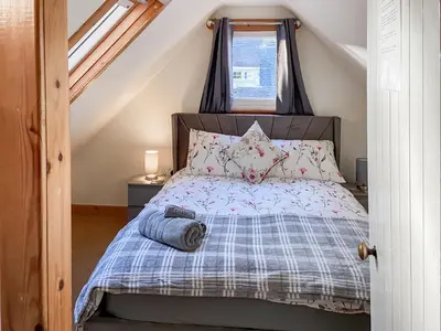 a bedroom with a bed with a blue comforter at Cosy Cottage in Lamlash