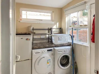 a laundry room with a washer and dryer and a window at Cosy Cottage in Lamlash