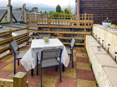 a table with a white table cloth on a patio at Cosy Cottage in Lamlash