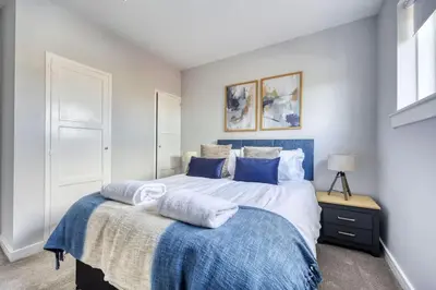 a bedroom with a large bed with blue and white sheets at Charming Terrace House for Relaxing Retreat in Dumbarton