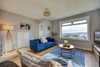 a living room with a blue couch and a window at Charming Terrace House for Relaxing Retreat in Dumbarton