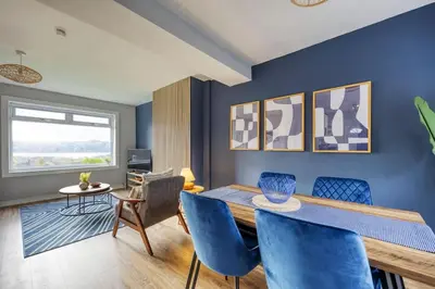a dining room with blue walls and a table and chairs at Charming Terrace House for Relaxing Retreat in Dumbarton