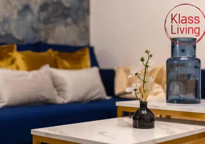 a living room with a blue couch and a vase with flowers at Colt Apartment by Klass Living Coatbridge in Glenboig