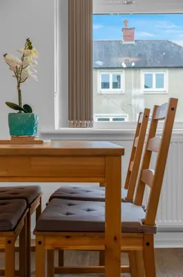 a dining room table with two chairs and a window at Vacant Nests The Grampian Free Wifi in Wishaw