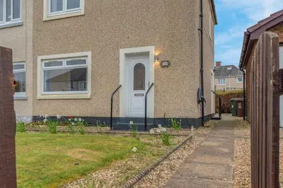 a house with a white door on the side of it at Vacant Nests The Grampian Free Wifi in Wishaw