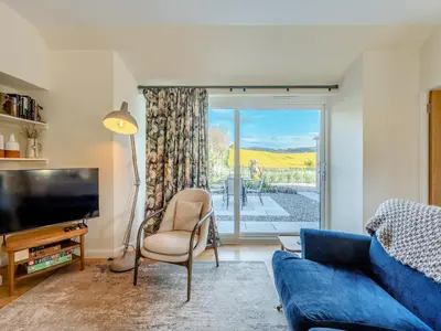 a living room with a blue couch and a tv at Newbigging Farm Cottage in Auchterarder