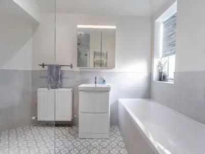 a white bathroom with a tub and a sink and a bath tub at Newbigging Farm Cottage in Auchterarder