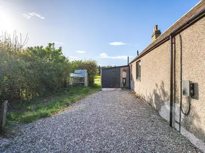 a person standing in front of a garage at Newbigging Farm Cottage in Auchterarder
