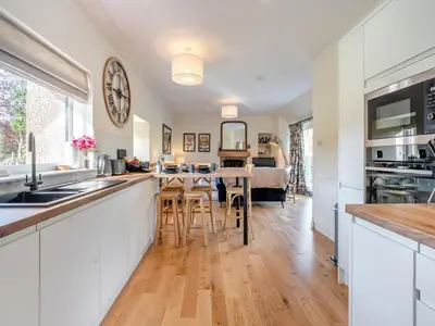 a kitchen and living room with a counter and a table at Newbigging Farm Cottage in Auchterarder