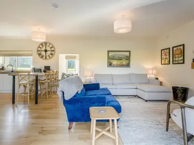 a living room with a blue couch and a table at Newbigging Farm Cottage in Auchterarder
