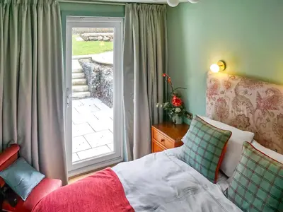 a bedroom with a bed and a sliding glass door at Alt Na Blathaich in Coirantee