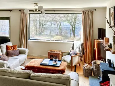 a living room with a couch and a large window at Alt Na Blathaich in Coirantee