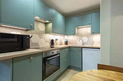 a kitchen with blue cabinets and a table at Quiet City Centre, King & Sofa Bed in Glasgow