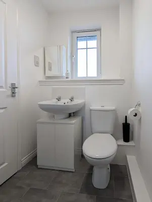 a white bathroom with a toilet and a sink at Pilmuir Apartment 3 bed 2 bath in Dunfermline
