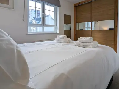 a white bed with towels on top of it at Pilmuir Apartment 3 bed 2 bath in Dunfermline