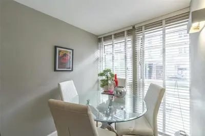 a dining room with a glass table and white chairs at Modern Main Door Flat Edinburgh City Center in Edinburgh