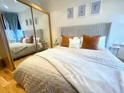 a bedroom with a large bed with a large mirror at Glasgow City - Large Stylish 2 Bed Flat in Unique Ibrox Location Walking Distance to Subway and Free On-Street Parking in Glasgow
