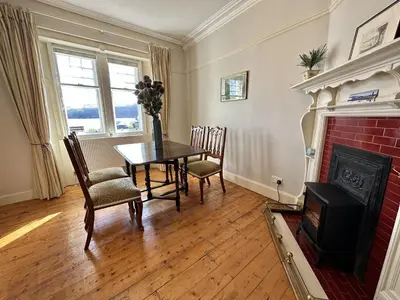 a dining room with a table and chairs and a fireplace at Traditional Inveraray Cottage - Amazing Loch Views in Inveraray