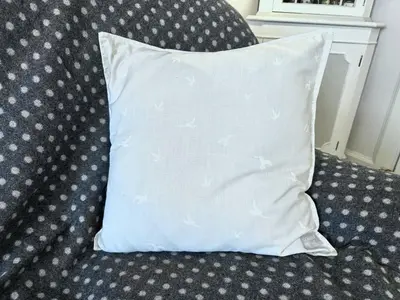 a white pillow sitting on a couch with at Traditional Inveraray Cottage - Amazing Loch Views in Inveraray