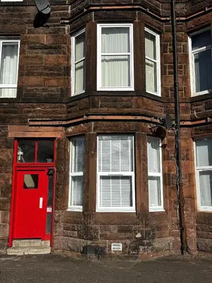 a red door on the side of a brick building at Castlegreen Lux Apartment in Dumbarton