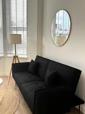 a black couch in a living room with a mirror at Castlegreen Lux Apartment in Dumbarton
