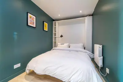 a bedroom with a large bed with a blue wall at Stylish Studio Finnieston City Centre Free Parking in Glasgow