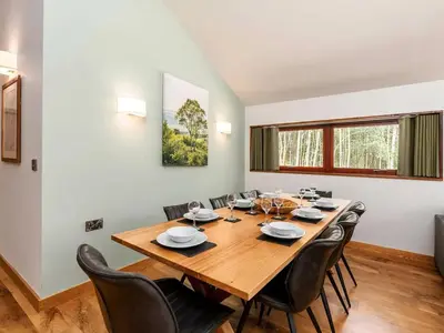 a dining room with a large wooden table and chairs at Strathyre, Ben Ledi Cabins - Forest Holidays in Callander