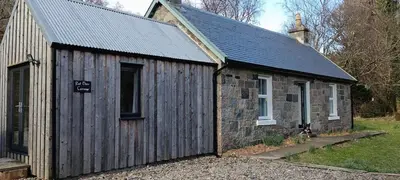 a small wooden building with a sign on it at Red Deer Cottage at Fanans in Oban