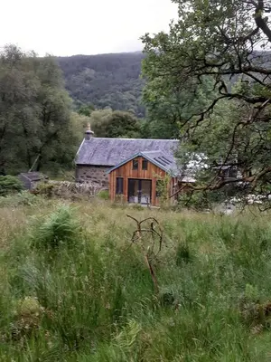 a wooden house in the middle of a field at Red Deer Cottage at Fanans in Oban