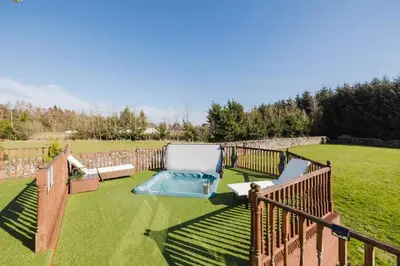 a backyard with a swimming pool and a fence at JOIVY Greenknowes Farmhouse with Hot Tub and Bar in Kelty