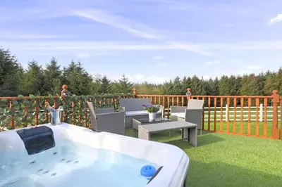 a bath tub sitting on top of a deck at JOIVY Greenknowes Cottage with Hot Tub & Fireplace in Kelty